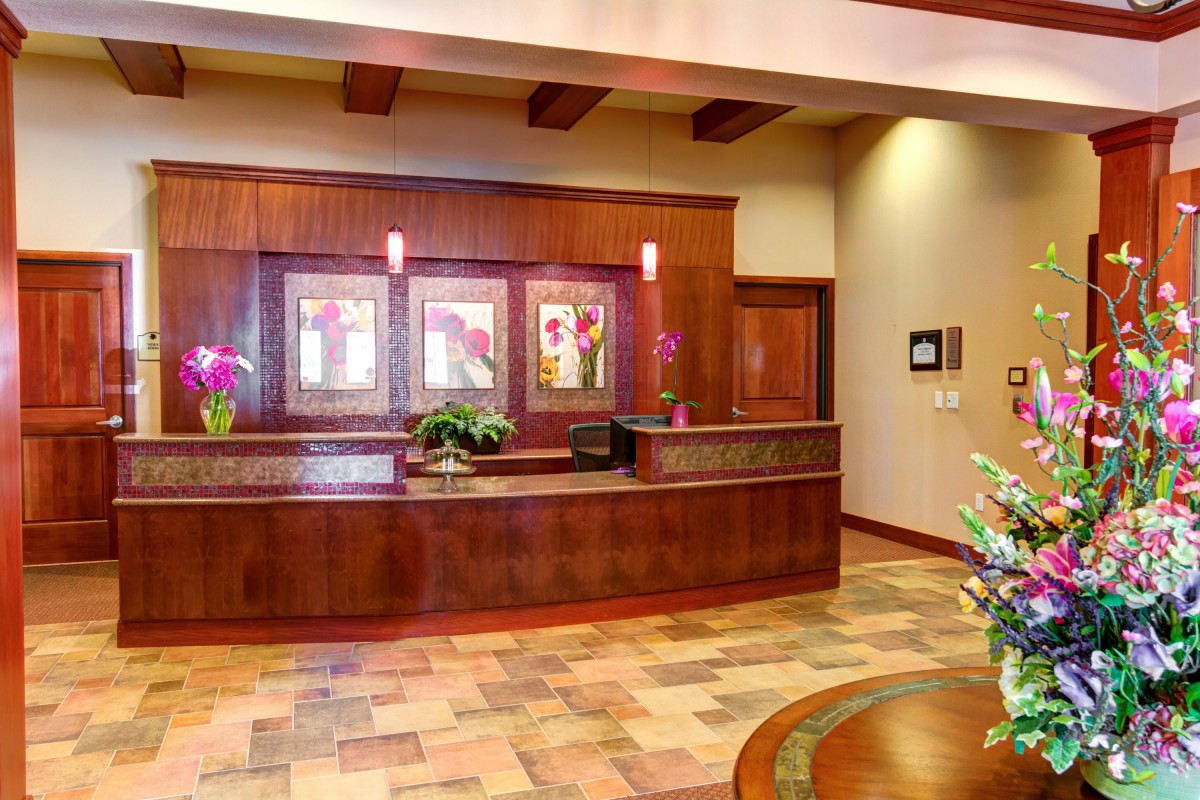 A well-designed reception area featuring a wooden desk, decorative lighting, and artwork on the walls.