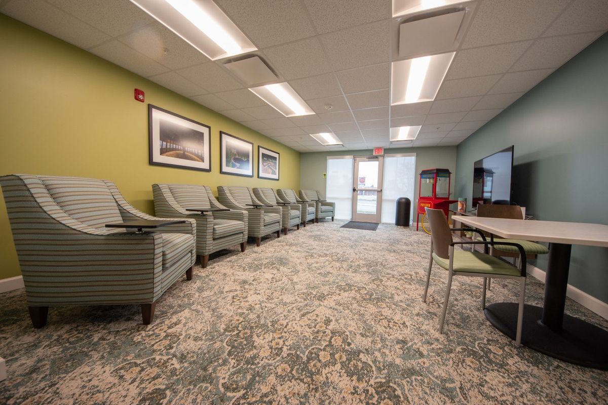 A well-lit waiting room with comfortable chairs and decorative paintings on the walls.