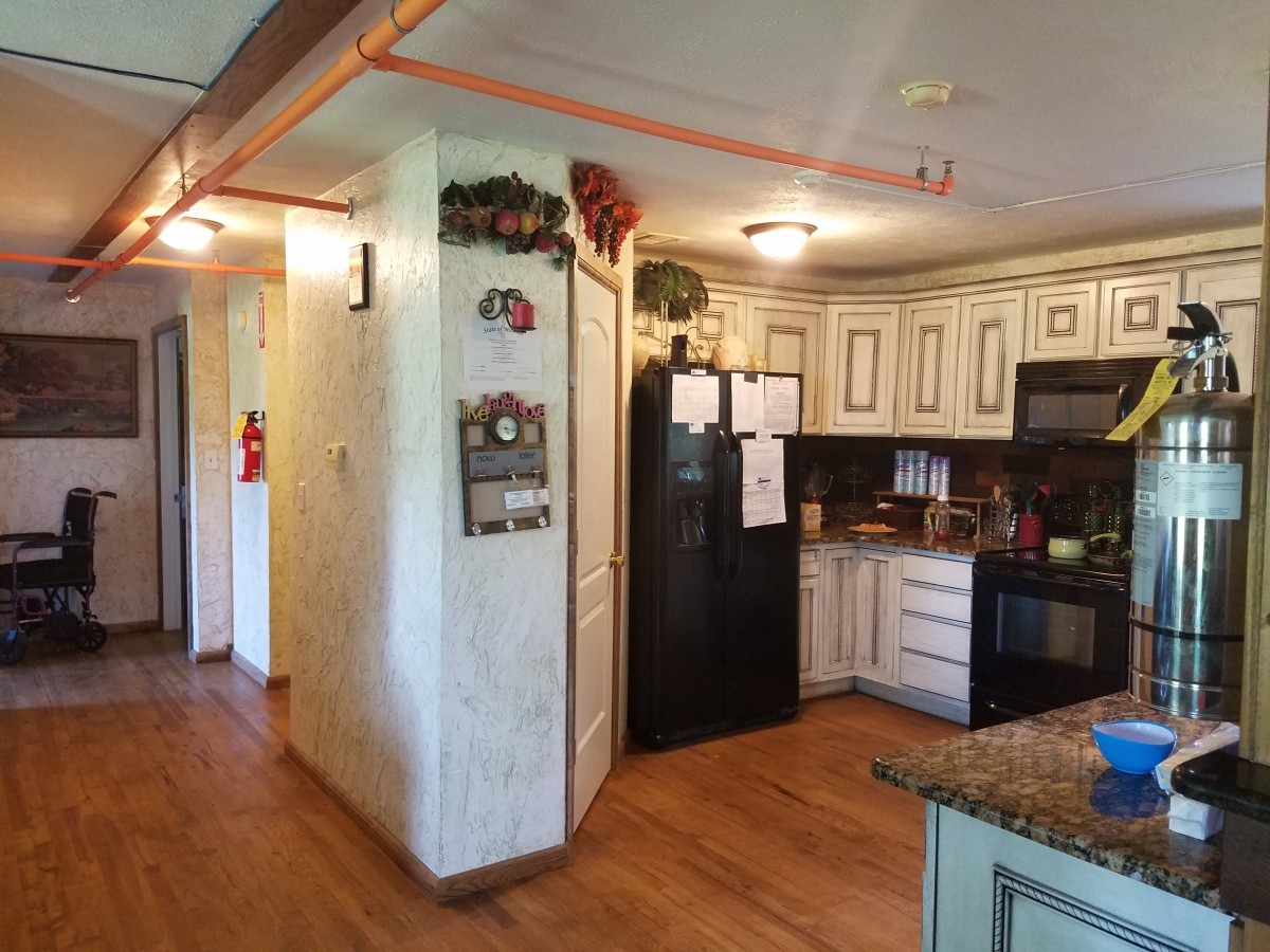 A cozy kitchen with wooden floors, white cabinets, and a black refrigerator.