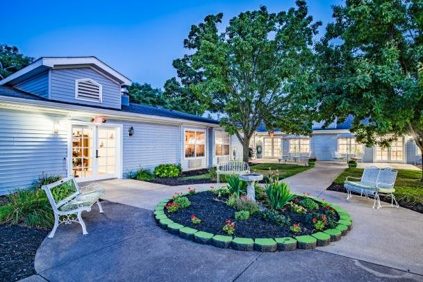 A well-lit building with a beautifully landscaped garden in the evening.