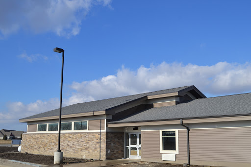 A modern building under a blue sky with scattered clouds.