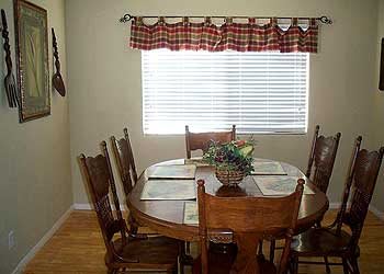 A cozy dining room with a wooden table and chairs near a window with plaid curtains.