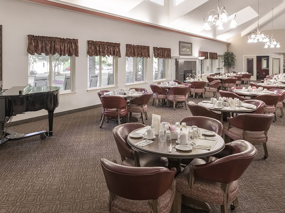 An elegant dining room with neatly arranged tables and a grand piano.