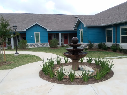 A beautiful residential building featuring a central fountain surrounded by landscaped greenery.
