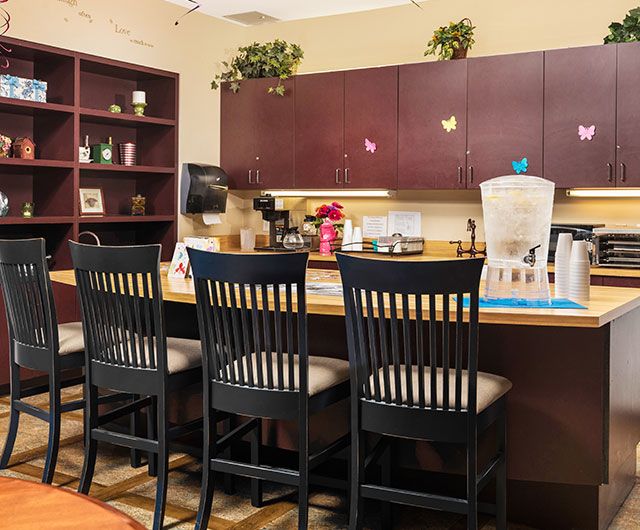 A cozy kitchen area with a counter and high chairs, featuring cabinets and a coffee maker.