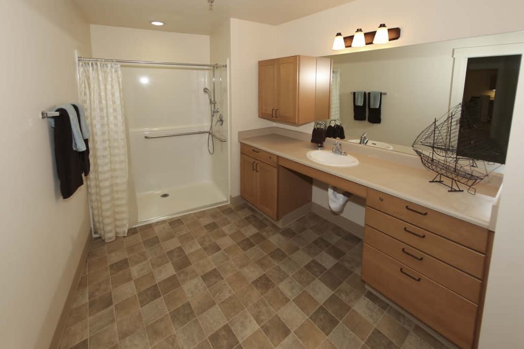 A modern bathroom with a walk-in shower, large mirror, and wooden cabinetry.
