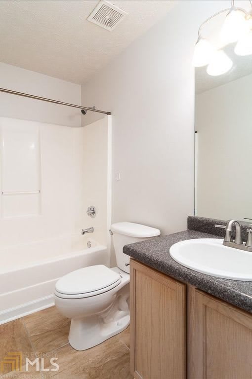 A clean and modern bathroom with a sink, toilet, and bathtub.