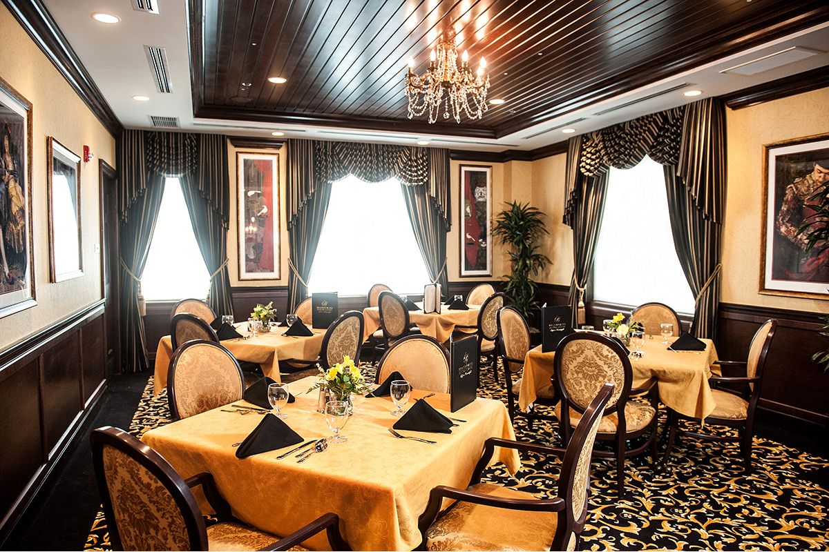 An elegant dining room with sophisticated table settings and a chandelier.