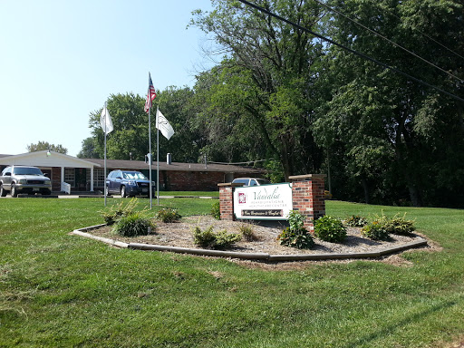 A welcoming entrance with signage, surrounded by greenery and flags.