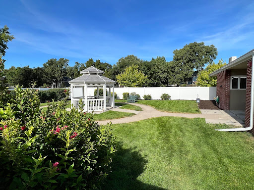 A serene garden featuring a gazebo surrounded by lush greenery and a clear blue sky.