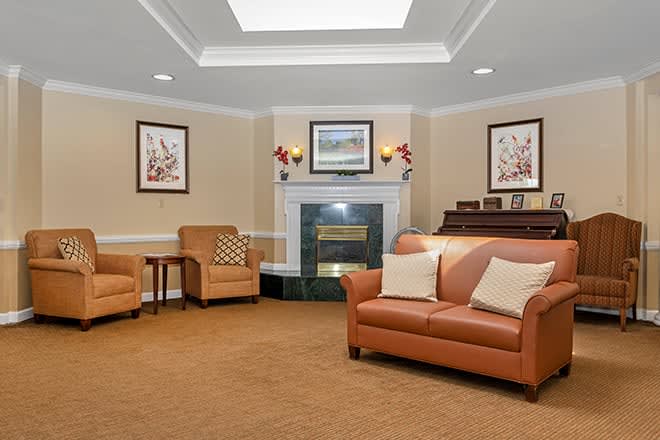 A cozy living room with a sofa, fireplace, and piano.