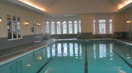 An indoor swimming pool with arched windows and a serene atmosphere.