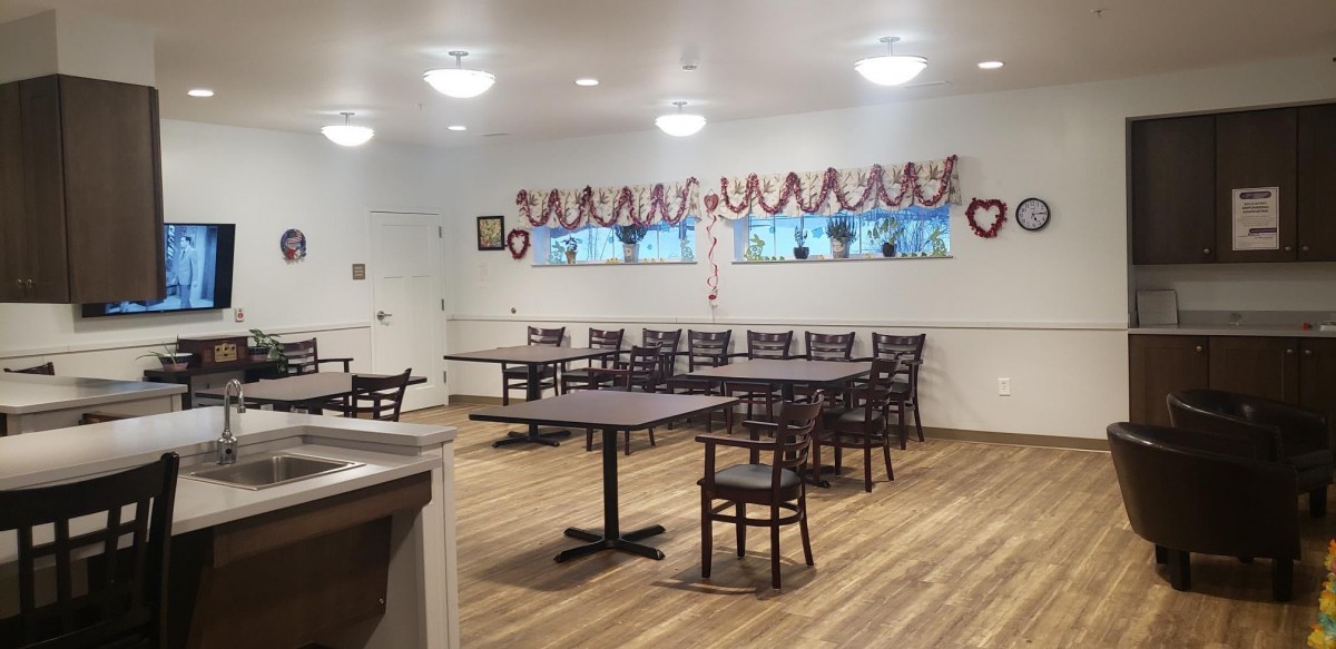 An empty dining room with tables and chairs, decorated with heart-themed garlands.
