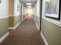 A long, carpeted hallway with closed doors and framed pictures on the walls.