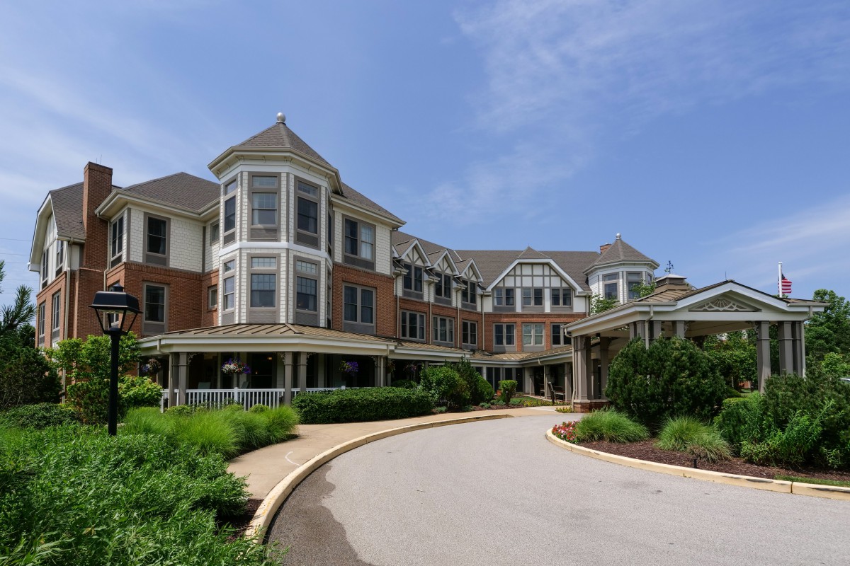 A Victorian-style building with a circular driveway on a clear day.