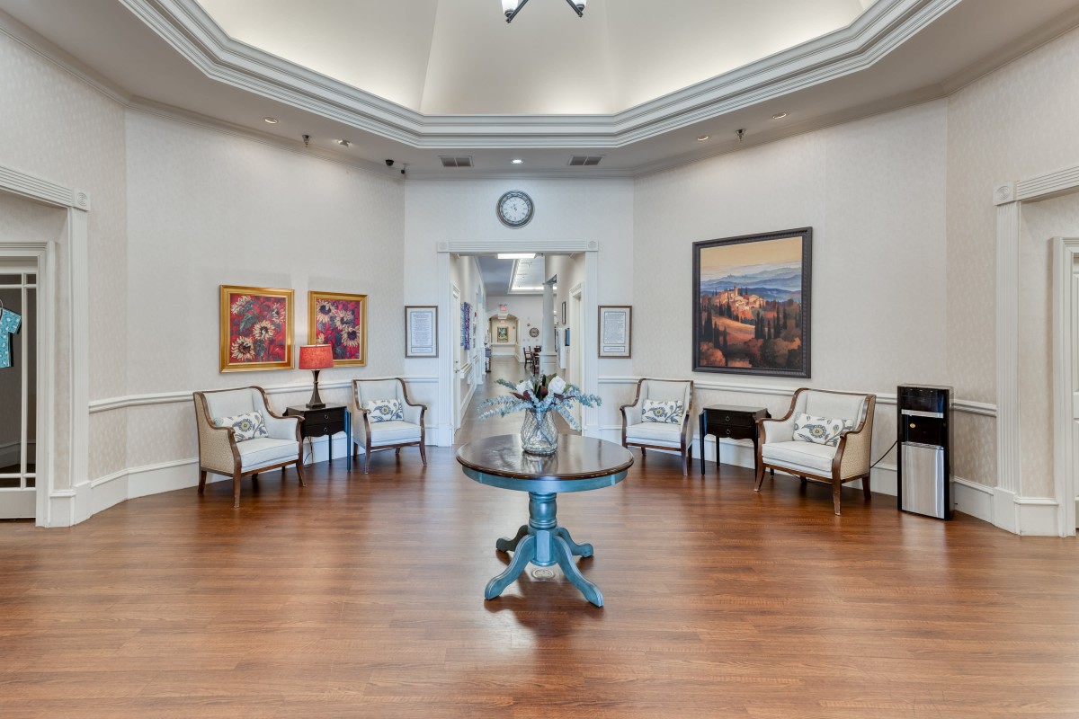 A modern waiting room featuring elegant chairs, vibrant artwork, a central table with decor, and a wall clock.