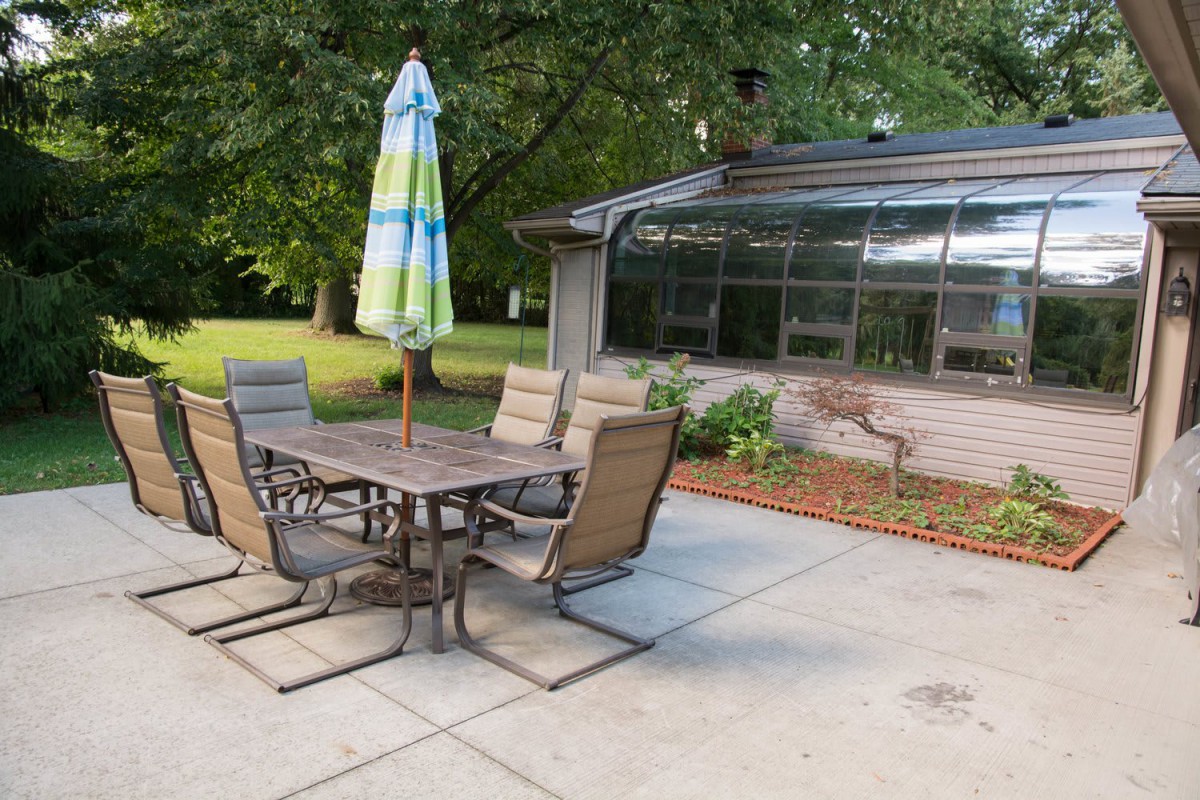 A cozy patio setup featuring a table with chairs and an umbrella, located in a backyard garden.