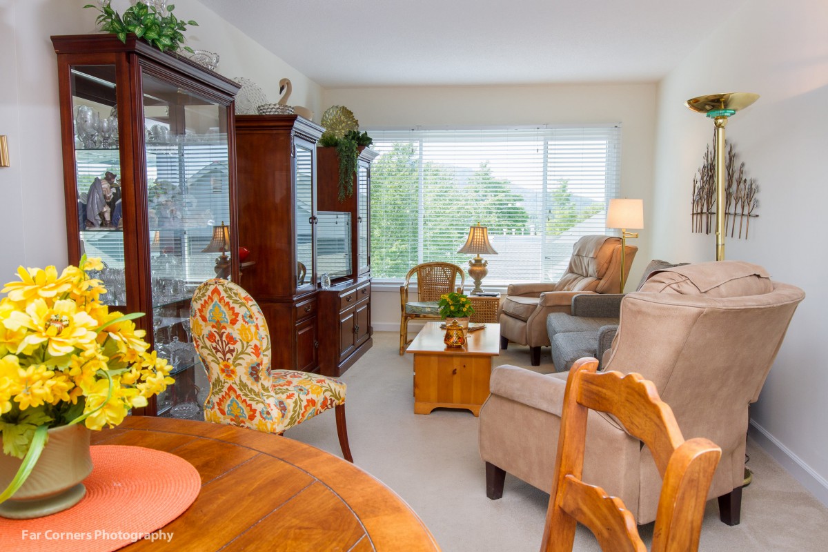 A bright and cozy living room with elegant wooden furniture and large windows offering a scenic view.