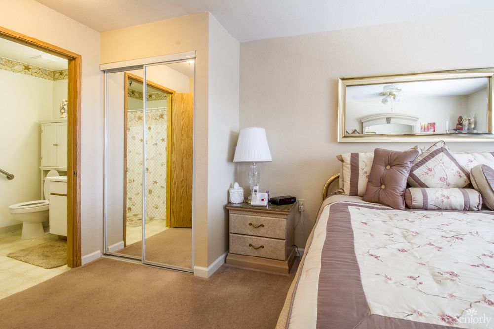 Cozy bedroom with a bed, nightstand, and mirror closet doors.
