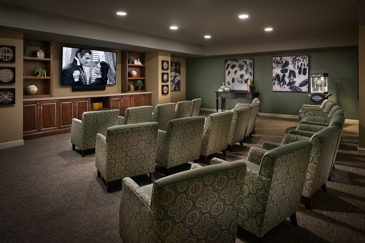 A cozy home theater room with patterned chairs and a large screen for watching movies.