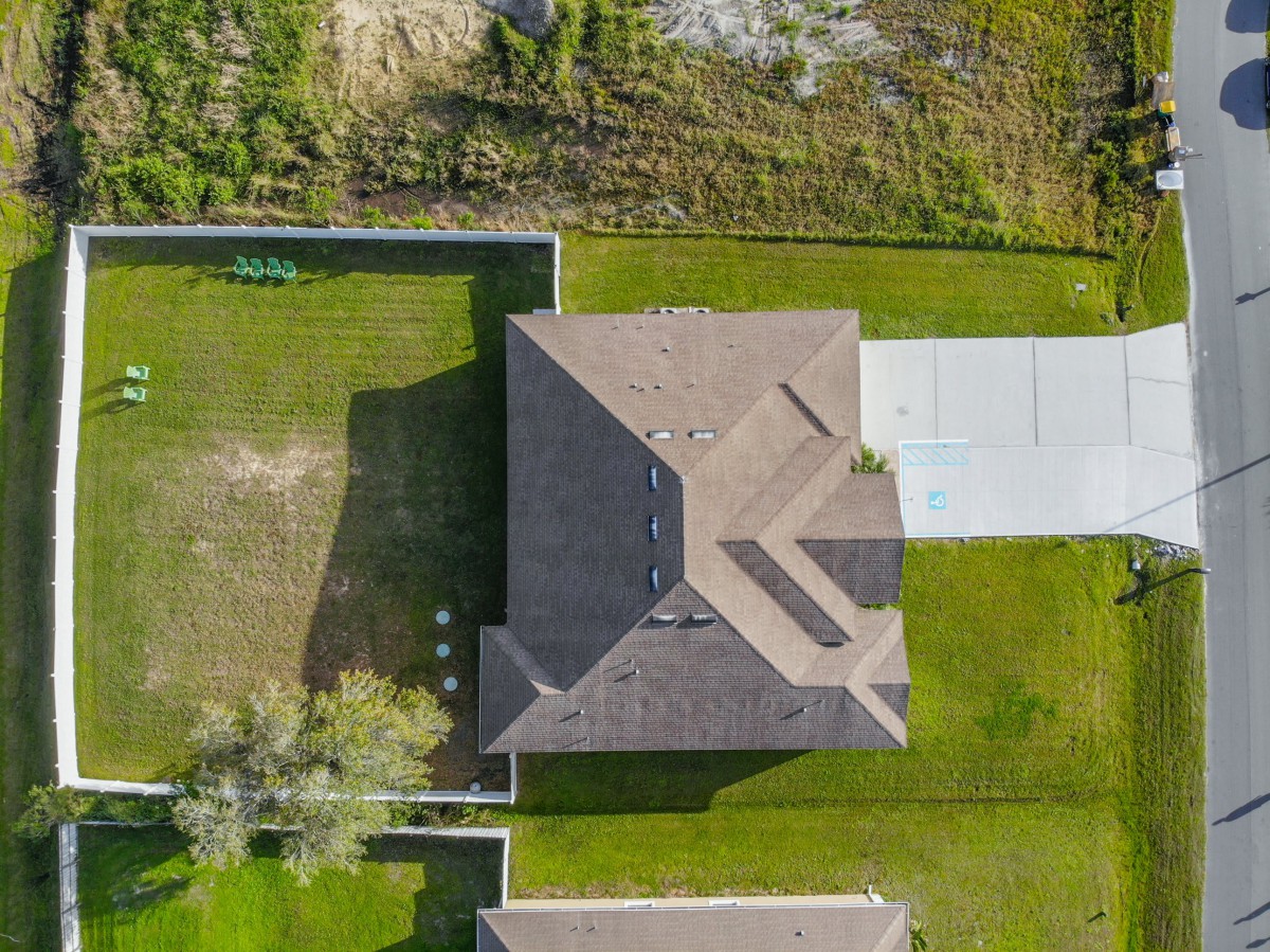 Aerial view of a house with a fenced backyard and driveway.