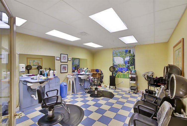 A well-lit hair salon interior with barber chairs and mirrors on a checkered floor.