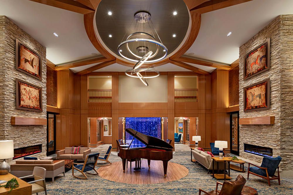 A modern lobby with a grand piano and elegant chandelier.