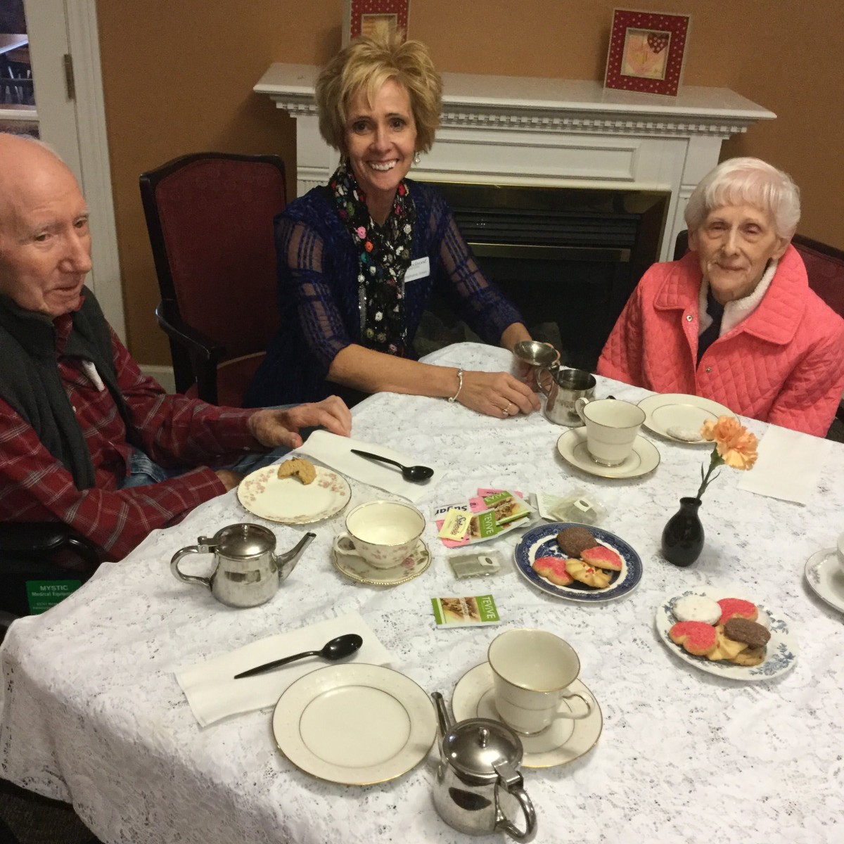 Three people sitting at a table enjoying tea together.