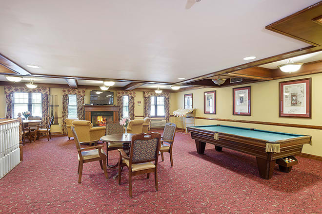 A cozy recreation room with a pool table, seating area, and fireplace.