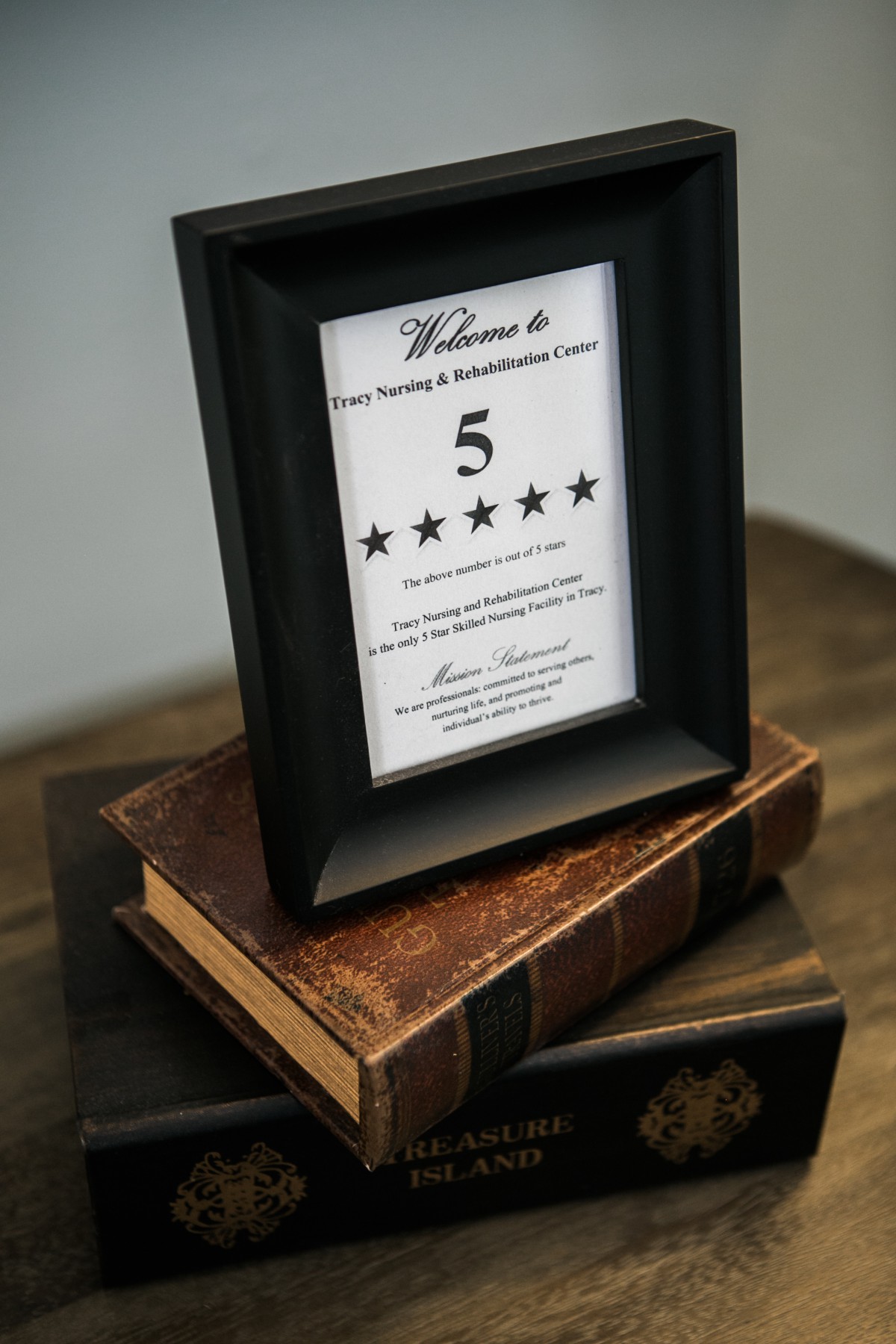 Framed five-star certificate displayed on a stack of vintage books.