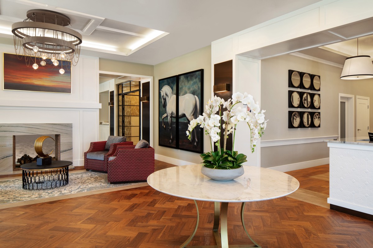 A modern living room with elegant decor, featuring a round table with orchids, artwork on the walls, and comfortable seating.