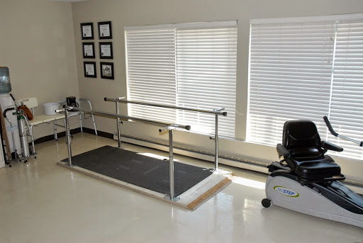 A rehabilitation therapy room equipped with a walking barre and exercise bike.