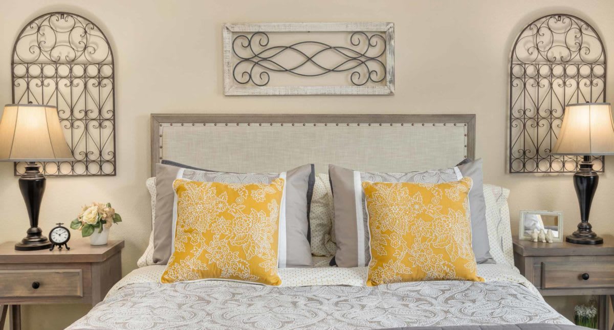 A cozy bedroom with a decorative headboard and vibrant yellow pillows.