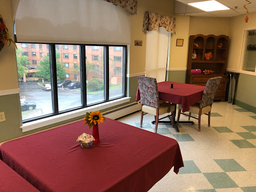 A bright dining area featuring tables with red tablecloths and a view of the outside.