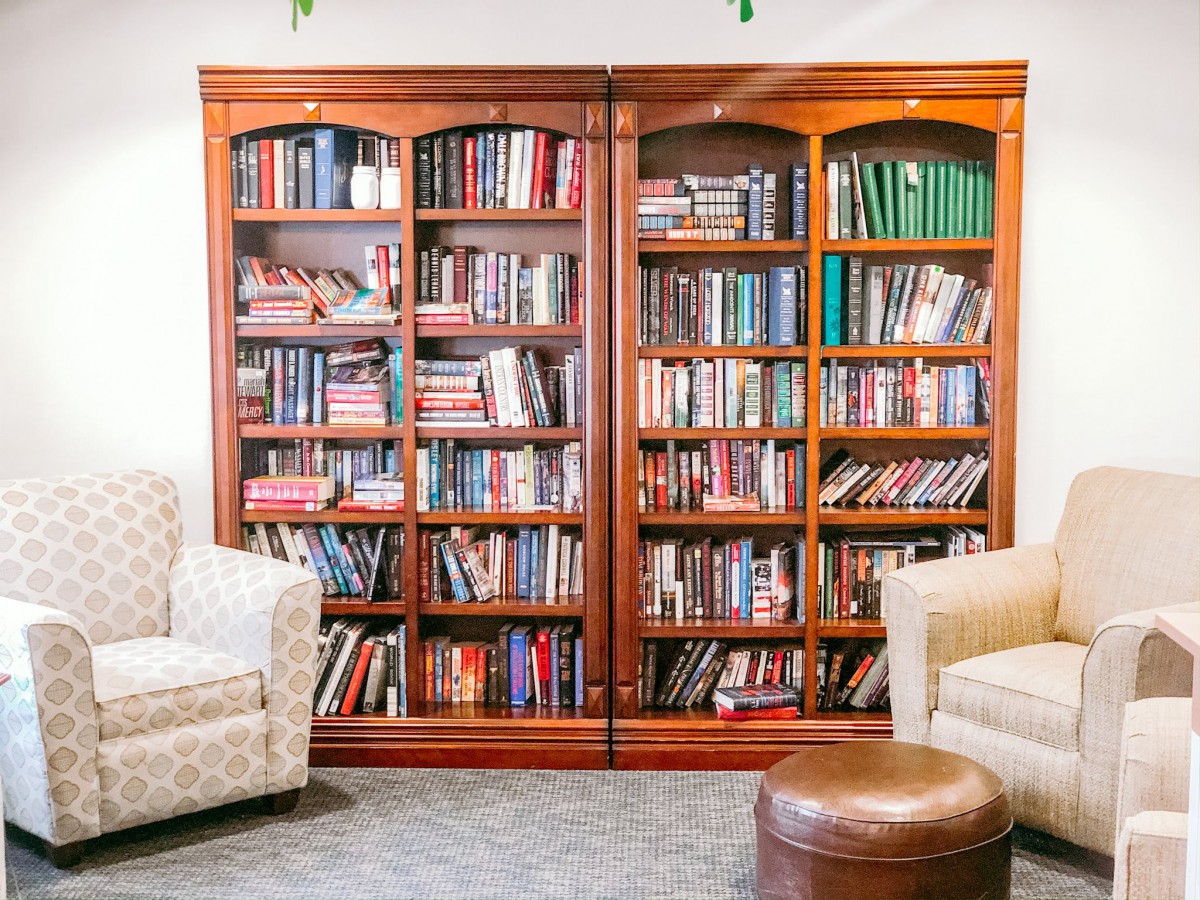 A cozy reading area featuring a large wooden bookshelf filled with books, flanked by comfortable chairs.