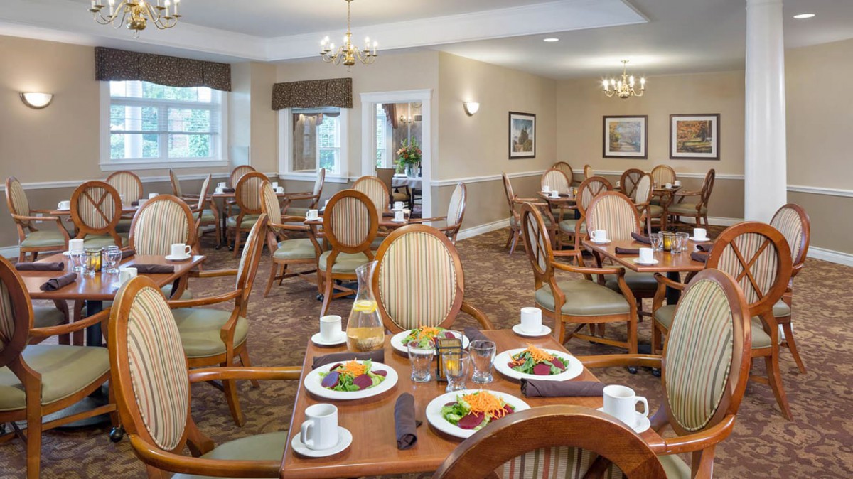 A well-arranged dining room with tables set for a meal, featuring elegant chairs and plates of food.