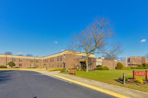 A modern school building surrounded by a clear blue sky and a well-kept lawn.