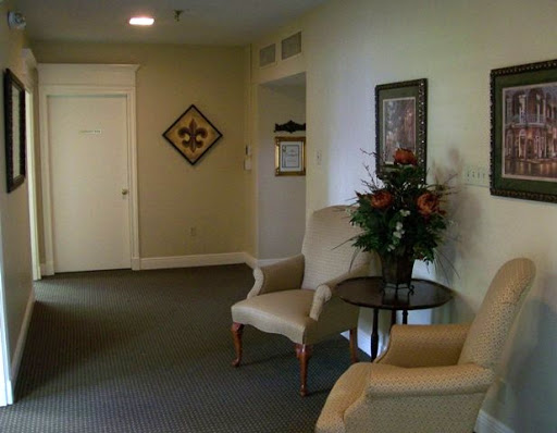 A cozy waiting area featuring comfortable chairs, decorative art on the walls, and a small table with flowers.