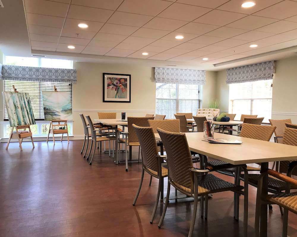 A well-lit meeting room with conference tables and chairs, featuring large windows for natural light.