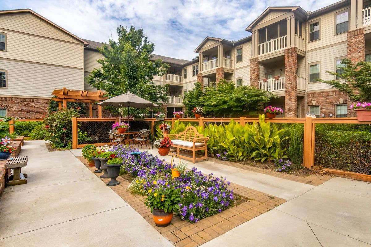 A beautifully landscaped garden with flowers and outdoor seating in a residential apartment complex.