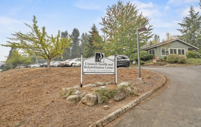 An exterior view of a building with a sign reading 'General Practice and Administration Center', surrounded by trees and parked cars.