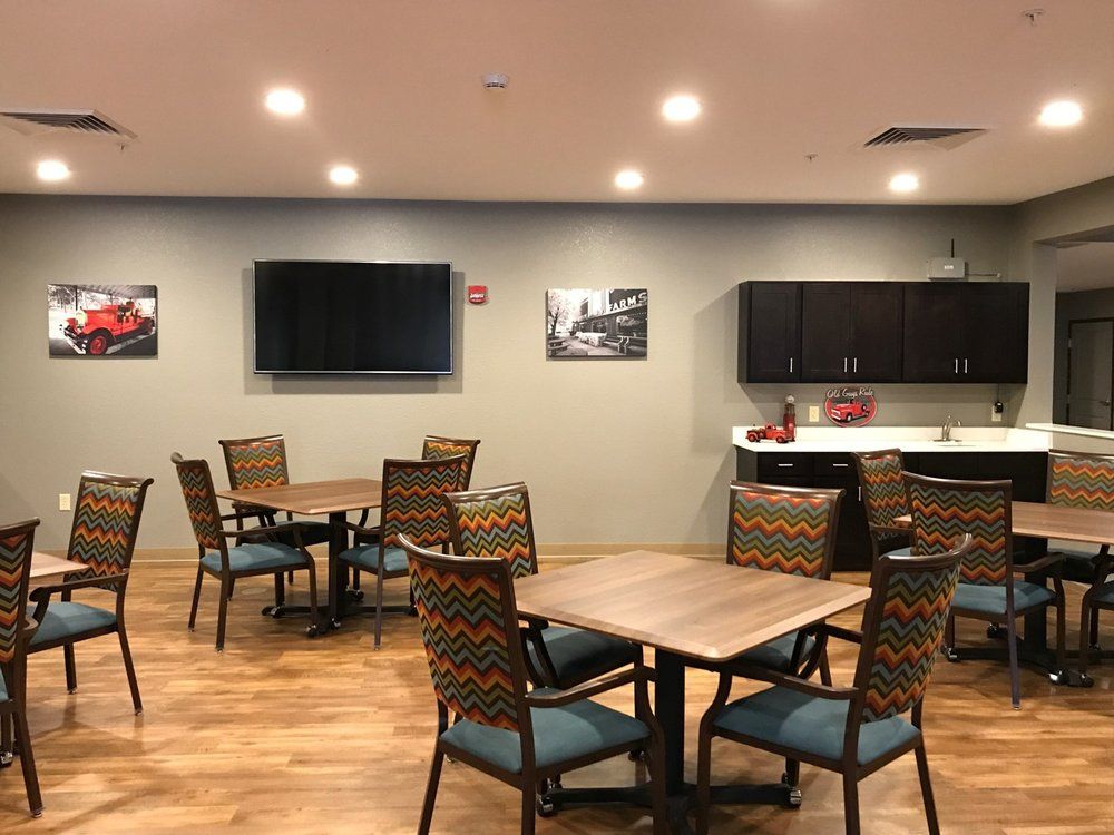 A modern dining area with several tables, chairs, a television, and a kitchenette.