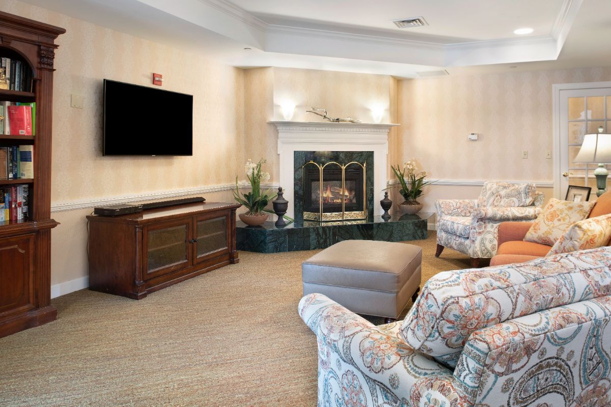 A cozy living room with a fireplace, sofa, and mounted television.