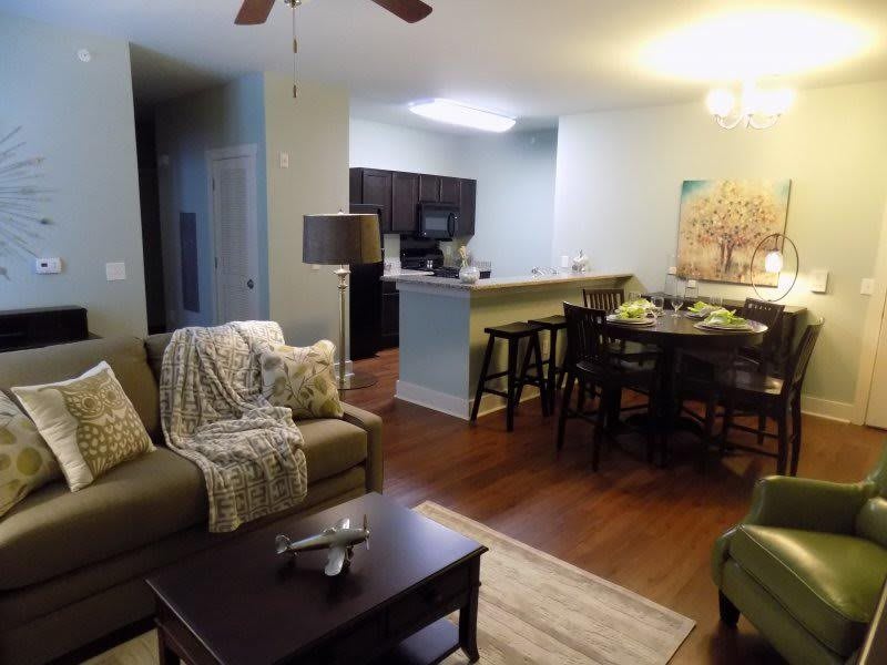 A cozy open-plan living area featuring a comfortable sofa, coffee table, and a dining area with bar stools overlooking the kitchen.
