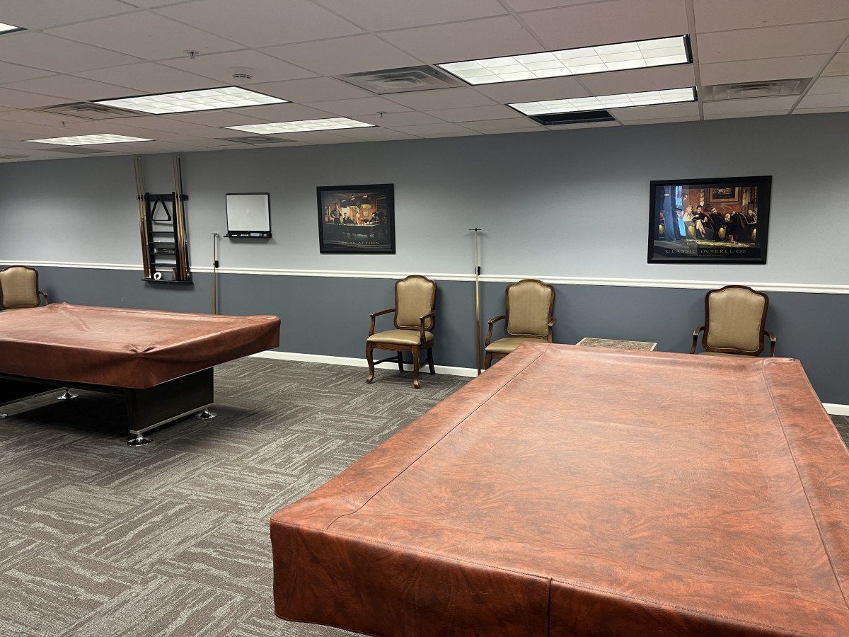 A spacious conference room with covered tables, chairs, and framed artwork on the walls.