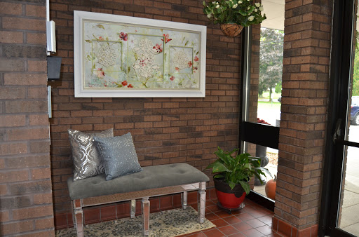 A cozy corner featuring a stylish bench, decorative artwork, and greenery against a rustic brick wall.