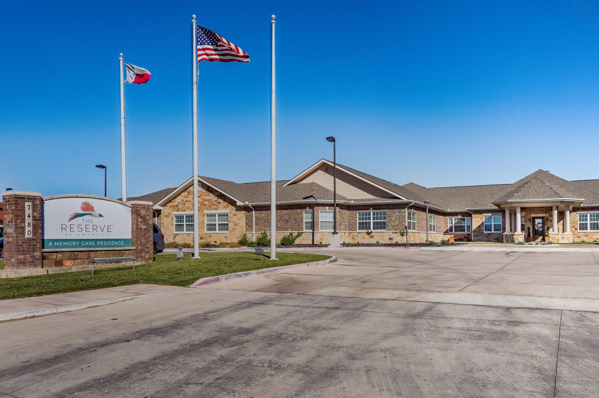 A one-story building with three flags in front, set against a clear blue sky.