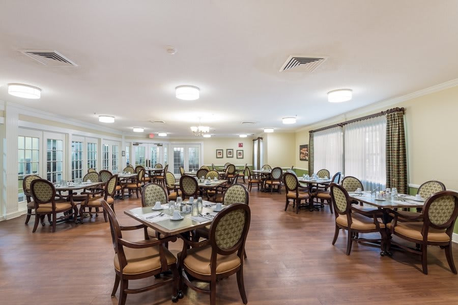 Spacious dining area with multiple tables and chairs, featuring wood flooring and soft lighting.