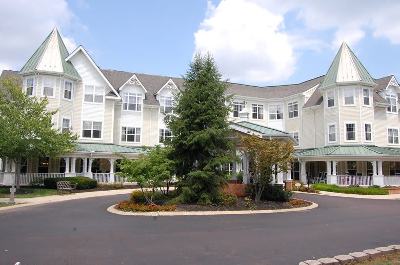 A large, multi-story residential building surrounded by landscaped gardens and a circular driveway.