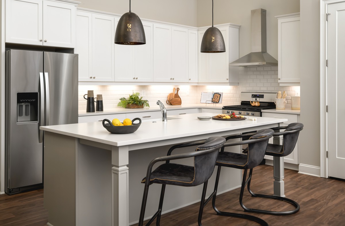 A modern kitchen with a central island, pendant lighting, and sleek white cabinetry.